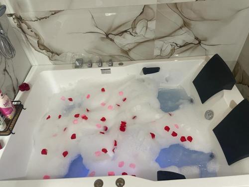 a bath tub filled with white liquid with red hearts at Qyteza Guest House & Camping in Renc