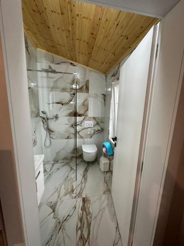 a bathroom with marble walls and a toilet at Qyteza Guest House & Camping in Renc