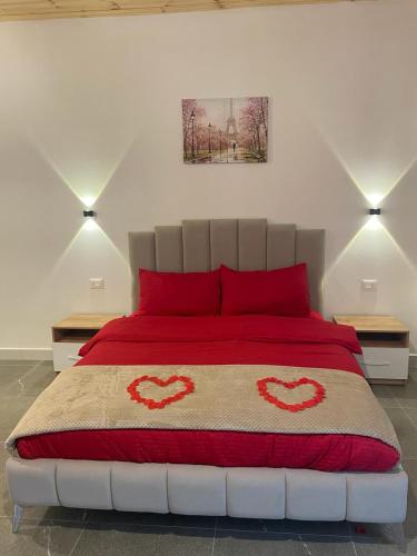 a bedroom with a red bed with two red pillows at Qyteza Guest House & Camping in Renc