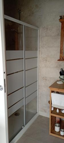 - une porte de douche en verre dans une pièce avec un comptoir dans l'établissement Bleu Bohème, à Lasson