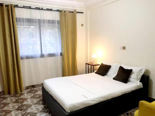 1 dormitorio con 1 cama blanca y ventana en Apartment PARIS, en Yaoundé