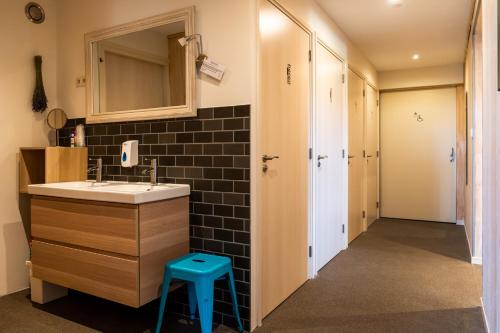a bathroom with a sink and a mirror and a stool at De Johanneshoeve in Westerhaar-Vriezenveensewijk