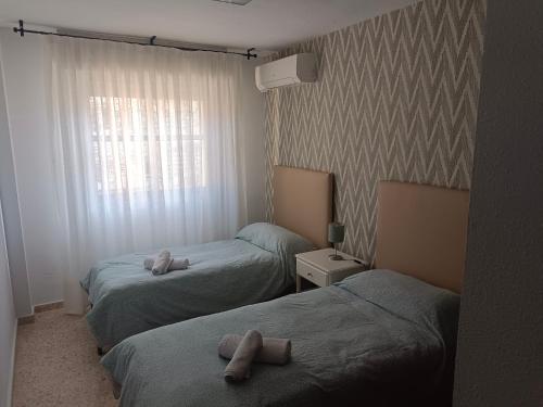twee bedden in een hotelkamer met handdoeken erop bij Piso para 6 junto al acueducto. A pasos del centro in Sevilla