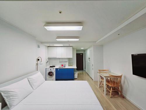 una camera con letto bianco e tavolo e una cucina di Jeoung's House a Busan