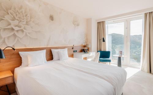 a bedroom with a white bed and a blue chair at Hotel Pieniny Grand Wellness & SPA - Destigo Hotels in Szczawnica