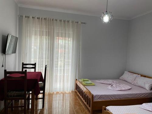 a bedroom with a bed and a table and a window at Eiffel's Guest House in Pogradec