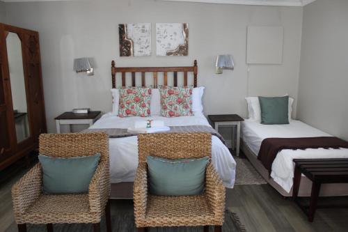 a bedroom with two beds and two chairs at Sir Roys Guest House in Port Elizabeth
