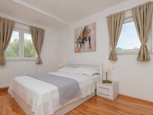 a white bedroom with a bed and two windows at Villa Drazana in Imotski