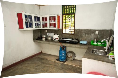 Mango villa في يوناواتونا: مطبخ مع دواليب حمراء وبيضاء ومغسلة