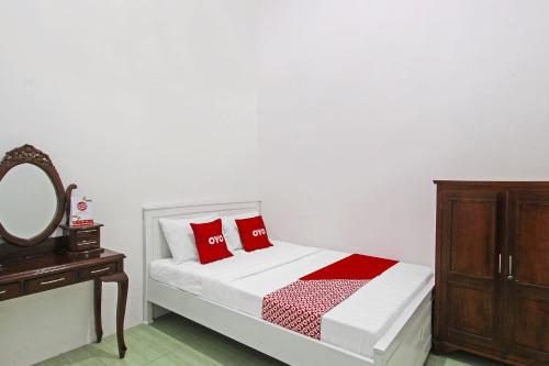 sypialnia z łóżkiem z czerwonymi poduszkami i lustrem w obiekcie OYO 91817 Hotel Grand New Si Jago w mieście Kebumen