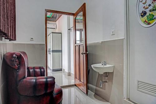 a bathroom with a leather chair and a sink at Super OYO 2226 Nurmega Jaya in Sukabumi