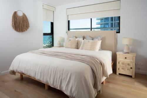 um quarto branco com uma cama grande com lençóis e almofadas brancos em Villa Sol - Luxury 3 Bedroom Villa in Kirra em Gold Coast