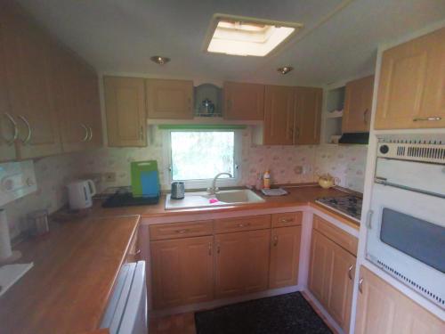 a kitchen with wooden cabinets and a sink and a window at Domki pod mazurskim niebem in Pilchy