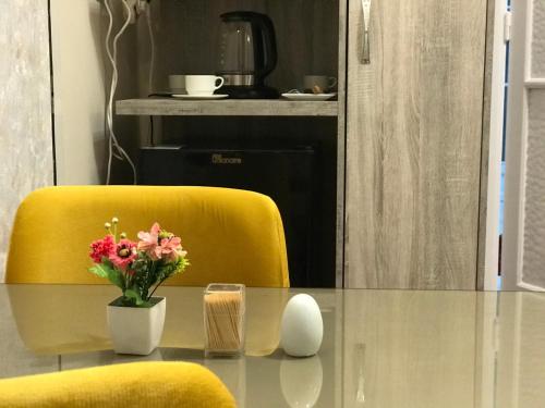 a table with a vase of flowers and a yellow chair at Yacoubian Suites in Cairo