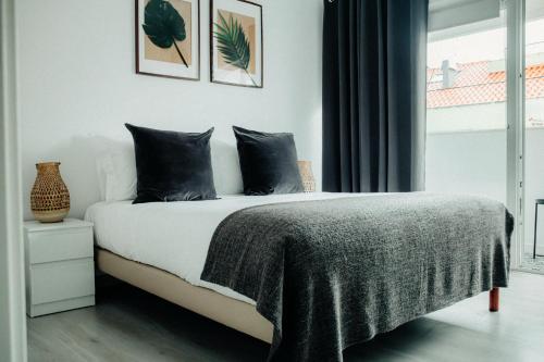 a bedroom with a bed with black pillows and a window at Belém Tejo - Memória by Local in Lisbon