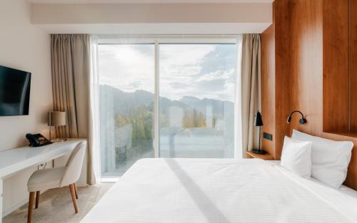 a bedroom with a bed and a large window at Hotel Pieniny Grand Wellness & SPA - Destigo Hotels in Szczawnica