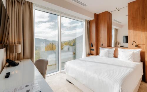 シュツァブニツァにあるPieniny Grand Szczawnicaのベッドと大きな窓が備わるホテルルームです。