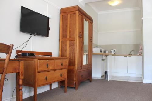 a large wooden cabinet with a television on a wall at Sir Roys Guest House in Port Elizabeth