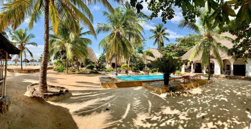 um resort com piscina e palmeiras em Mambo Ocean Resort em Pwani Mchangani