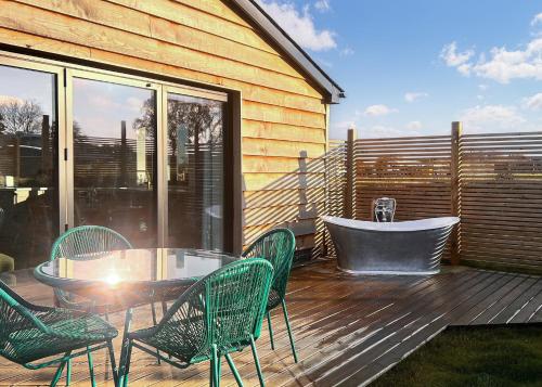 a deck with a table and chairs and a tub at Old Buckenham Country Park in Old Buckenham