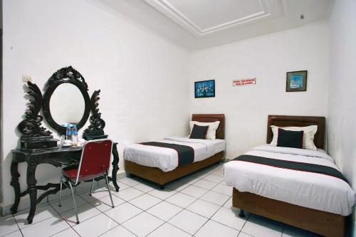 een slaapkamer met 2 bedden, een spiegel en een bureau bij OYO 93467 Wisma Olo Syariah in Padang