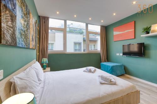 a bedroom with a bed and a flat screen tv at Modern Paceville Suites with WIFI & AC by 360 Estates in Paceville