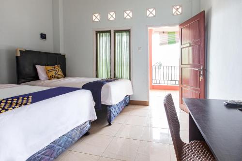 Cette chambre comprend deux lits, un bureau et une table. dans l'établissement SPOT ON 93430 Delta Bnb Residence, à Perabumulih