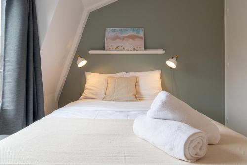 une chambre avec un lit avec des draps blancs et des serviettes dans l'établissement Vieux Lille - Appartement idéal pour 2 personnes, à Lille