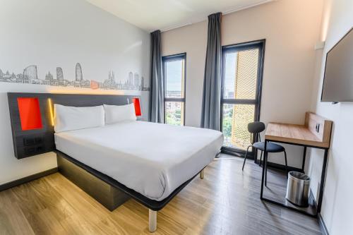 ロスピタレート・デ・リョブレガートにあるeasyHotel Barcelona Firaのベッド、デスク、窓が備わるホテルルームです。