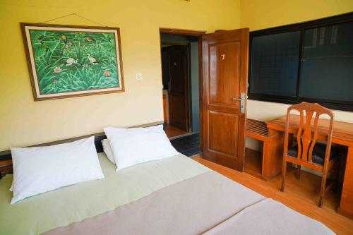 - une chambre avec un lit et un bureau avec une photo sur le mur dans l'établissement Pondok Sukamulus by GroRental, à Cihanjuang 1