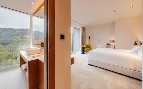 a bedroom with a bed and a large window at Hotel Pieniny Grand Wellness & SPA - Destigo Hotels in Szczawnica