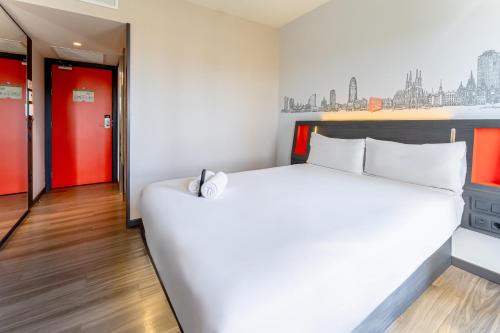 um quarto com uma cama branca e portas vermelhas em easyHotel Barcelona Fira em Hospitalet de Llobregat