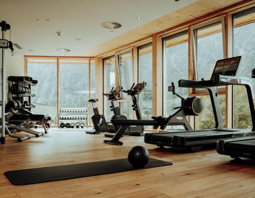 a gym with treadmills and exercise equipment in a room with windows at Familienresort Buchau in Maurach