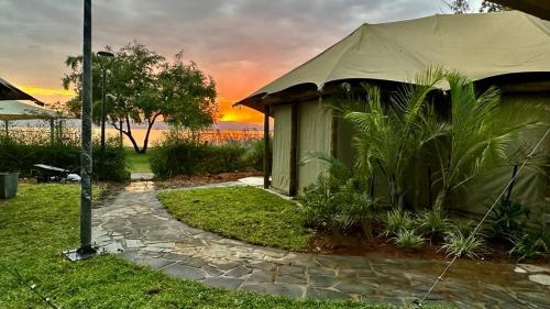 a tent in a yard with a sunset in the background at Doga Resort - דוגה ריזורט in Kinar