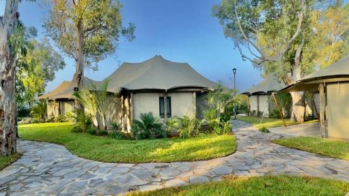 a house with a peaked roof and a cobblestone driveway at Doga Resort - דוגה ריזורט in Kinar