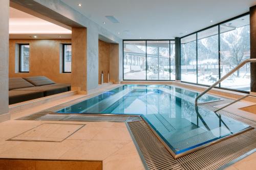 a swimming pool in a house with glass windows at Familienresort Buchau in Maurach