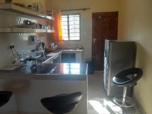 uma cozinha com um frigorífico de aço inoxidável e 2 bancos em Ngala Blessed Apartment em Melinde