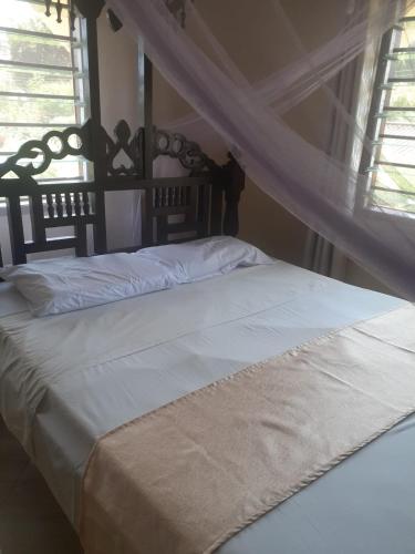 a bedroom with a white bed with a canopy at Ngala Blessed Apartment in Malindi
