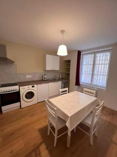 Il comprend une cuisine avec une table et des chaises blanches ainsi qu'une cuisine équipée d'une cuisinière. dans l'établissement 