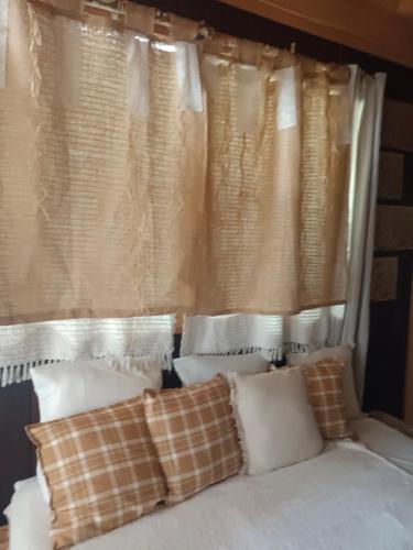a bed with pillows in front of a window at Chalet des secrets in Lyaud