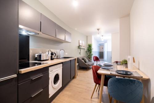 uma cozinha com uma máquina de lavar e secar roupa e uma mesa em Lille Centre: 2bed 2bath apartment! em Lille