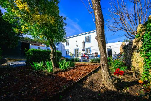 a white house with trees and flowers in a yard at Casa das Pedras Country Retreat in Santo António das Areias