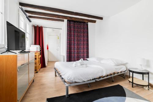 une chambre avec un lit et une télévision dans une pièce dans l'établissement Agréable studio cœur de paris - Paris 6 - 2P - FLAT-GUEST, à Paris