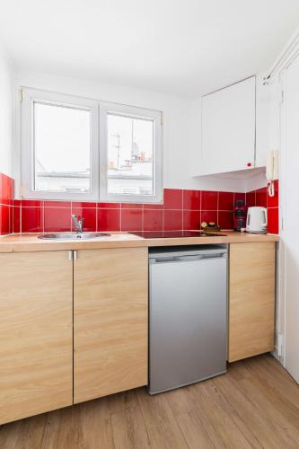 une cuisine avec des placards en bois et du carrelage rouge dans l'établissement Agréable studio cœur de paris - Paris 6 - 2P - FLAT-GUEST, à Paris