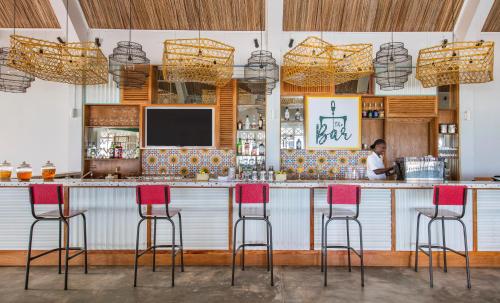 a bar with red chairs and a woman in a kitchen at C Rodrigues Mourouk in Rodrigues Island