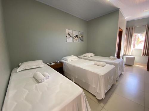 two beds in a room with white sheets at Pousada Mirante da Lua in Alto Paraíso de Goiás