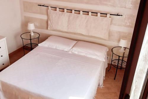 a white bed in a room with two lamps at A due passi dal Castello in Bosa