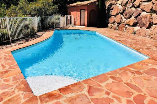 une piscine d'eau bleue et un mur en pierre dans l'établissement Superbe 3 pièces sur la baie de Théoule, à Théoule-sur-Mer