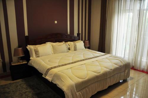 1 dormitorio con 1 cama grande con sábanas y almohadas blancas en VILLA MODERNE CHEZ YVONNE en Kigali