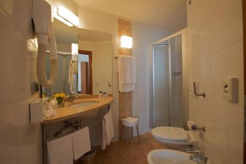 a bathroom with two sinks and a toilet and a shower at Best Western Hotel Fiera Verona in Verona